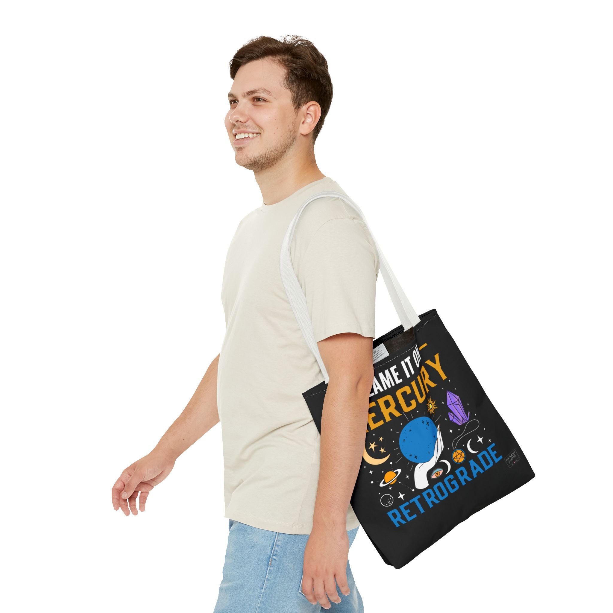 Man with white handle astrology tote bag next to laptop and books