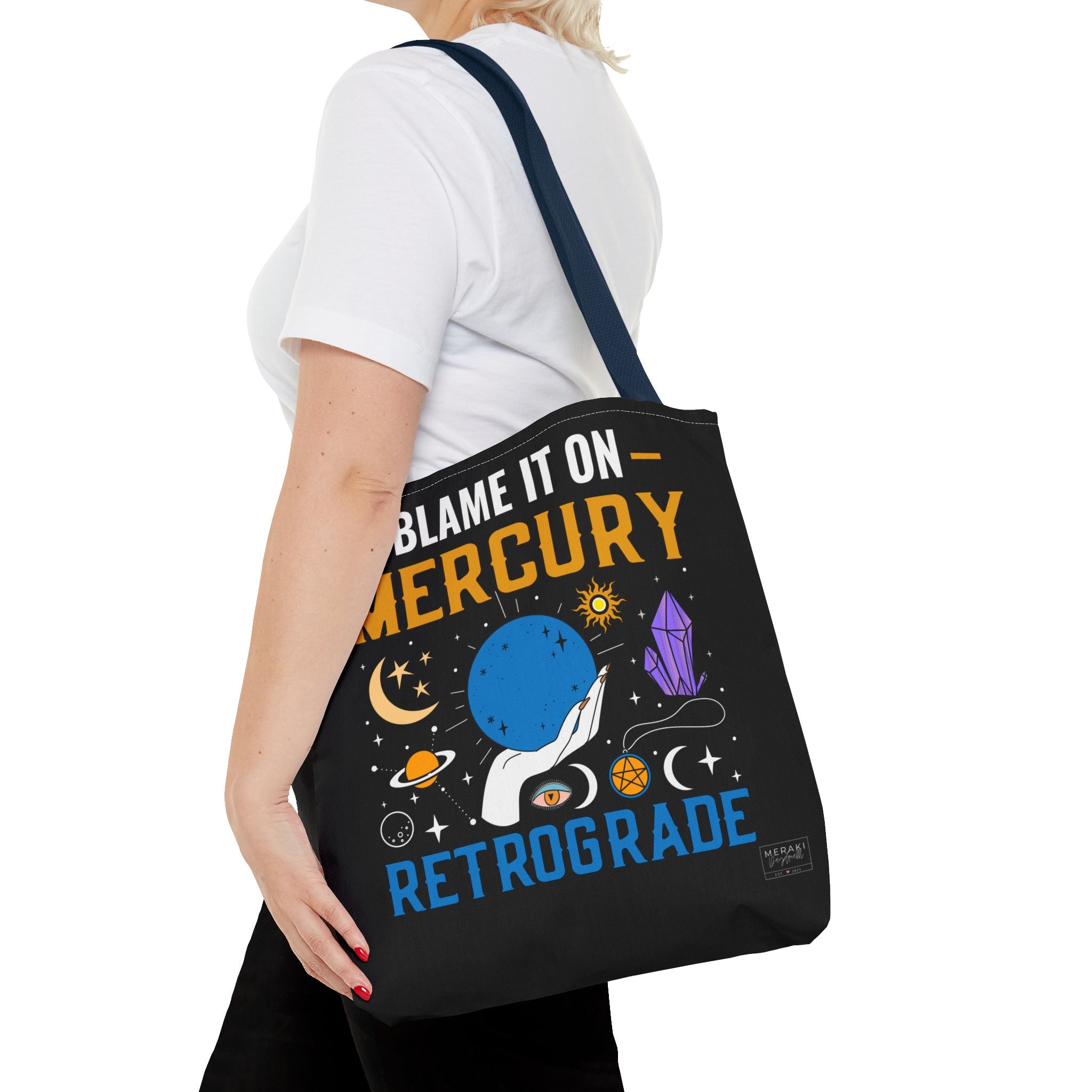 Woman walking with navy handle astrology tote and phone in hand