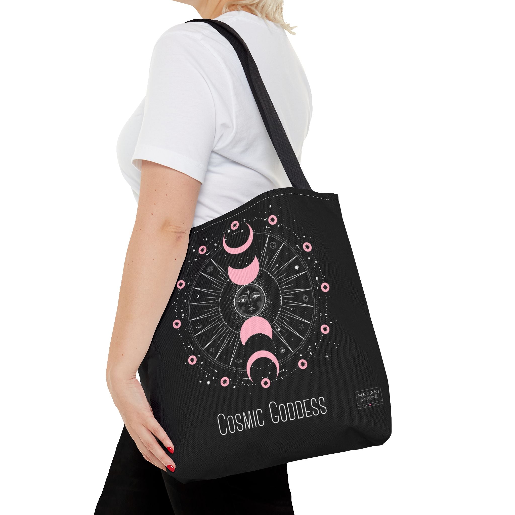 Woman wearing black handle Cosmic Goddess tote walking through garden